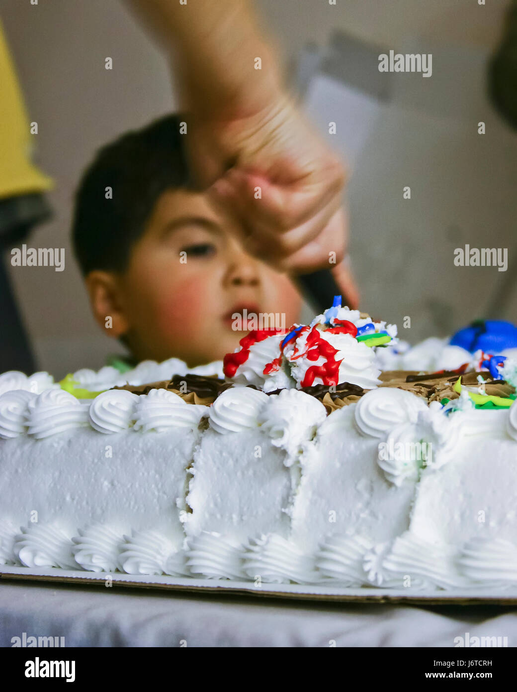 Junge beobachten Mama schneiden große Kuchen - USA Stockfoto