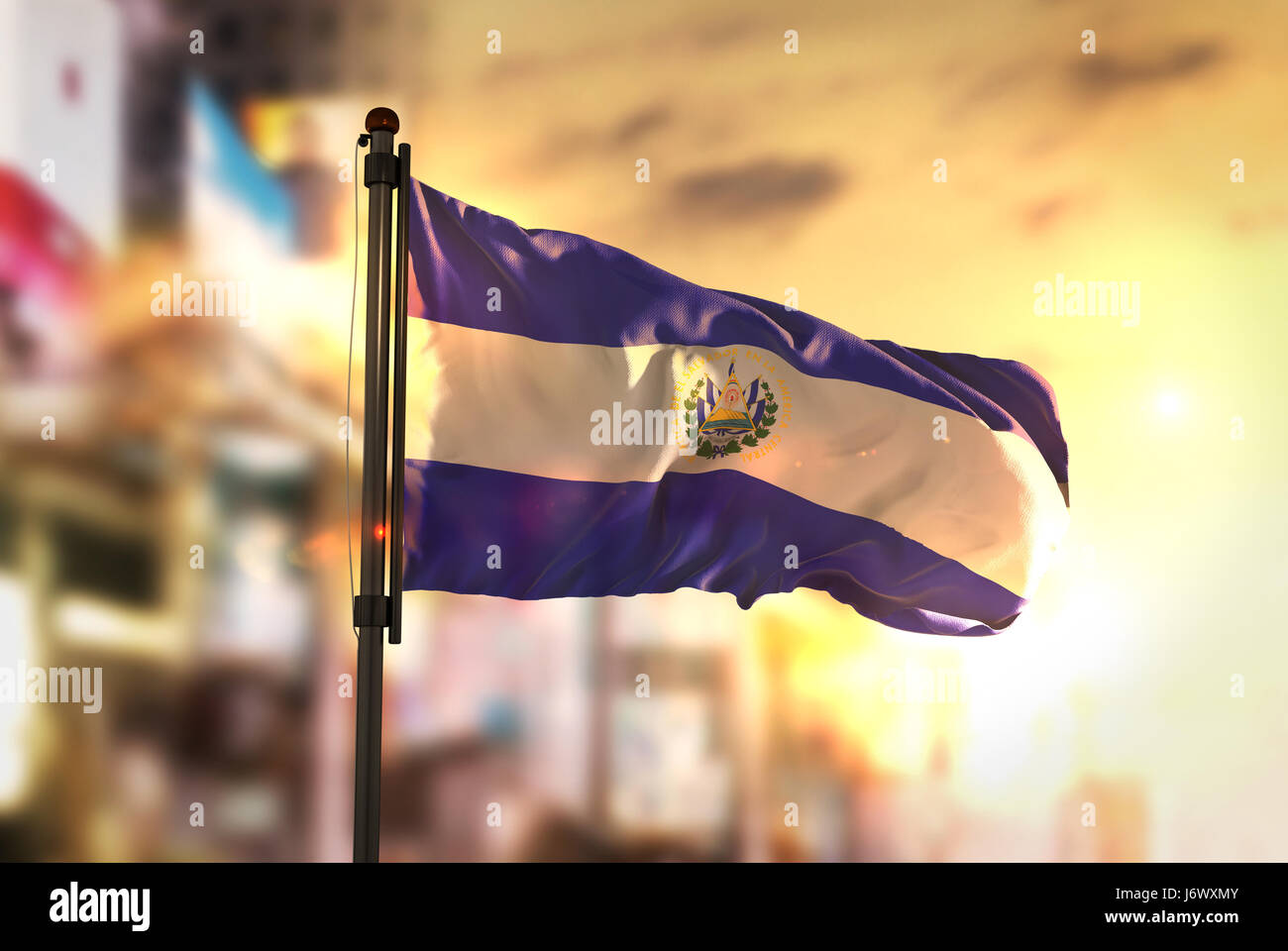 El Salvador Flagge gegen City unscharf Hintergrund bei Sonnenaufgang Hintergrundbeleuchtung Stockfoto