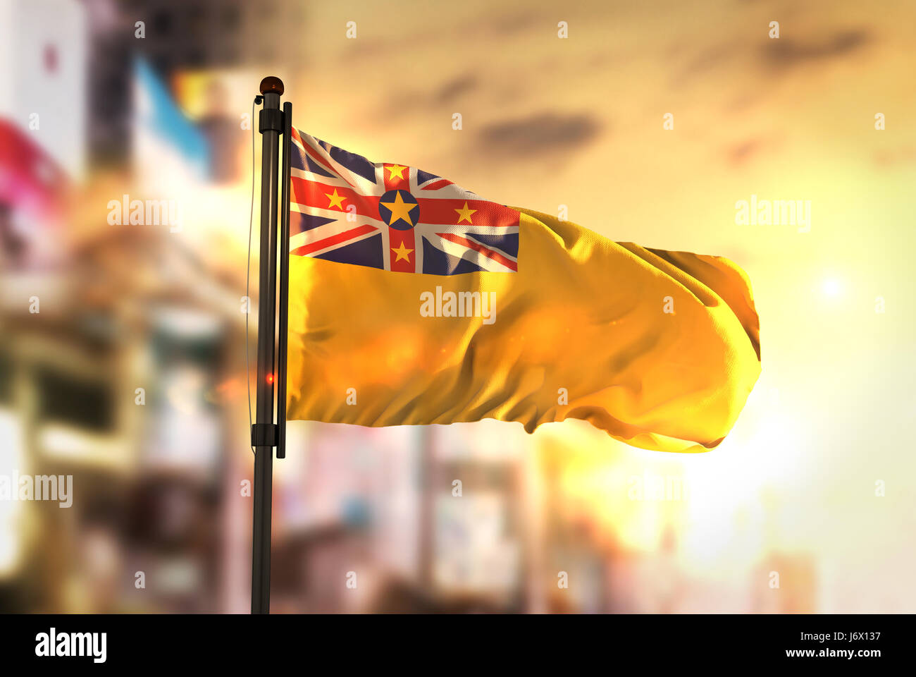 Niue Fahne gegen City unscharf Hintergrund bei Sonnenaufgang Hintergrundbeleuchtung Stockfoto