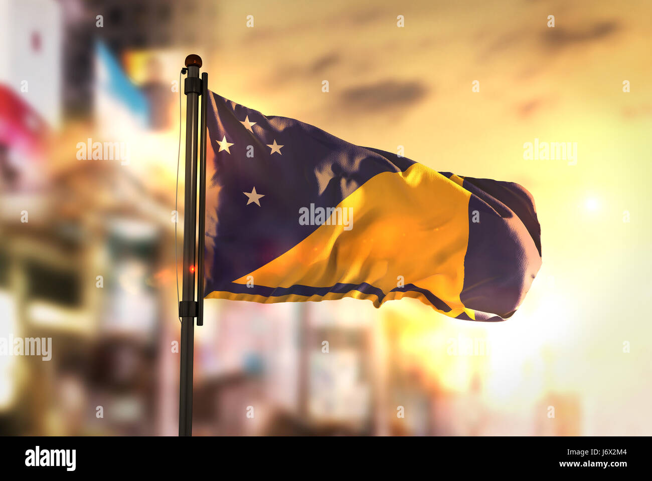Tokelau Fahne gegen City unscharf Hintergrund bei Sonnenaufgang Hintergrundbeleuchtung Stockfoto