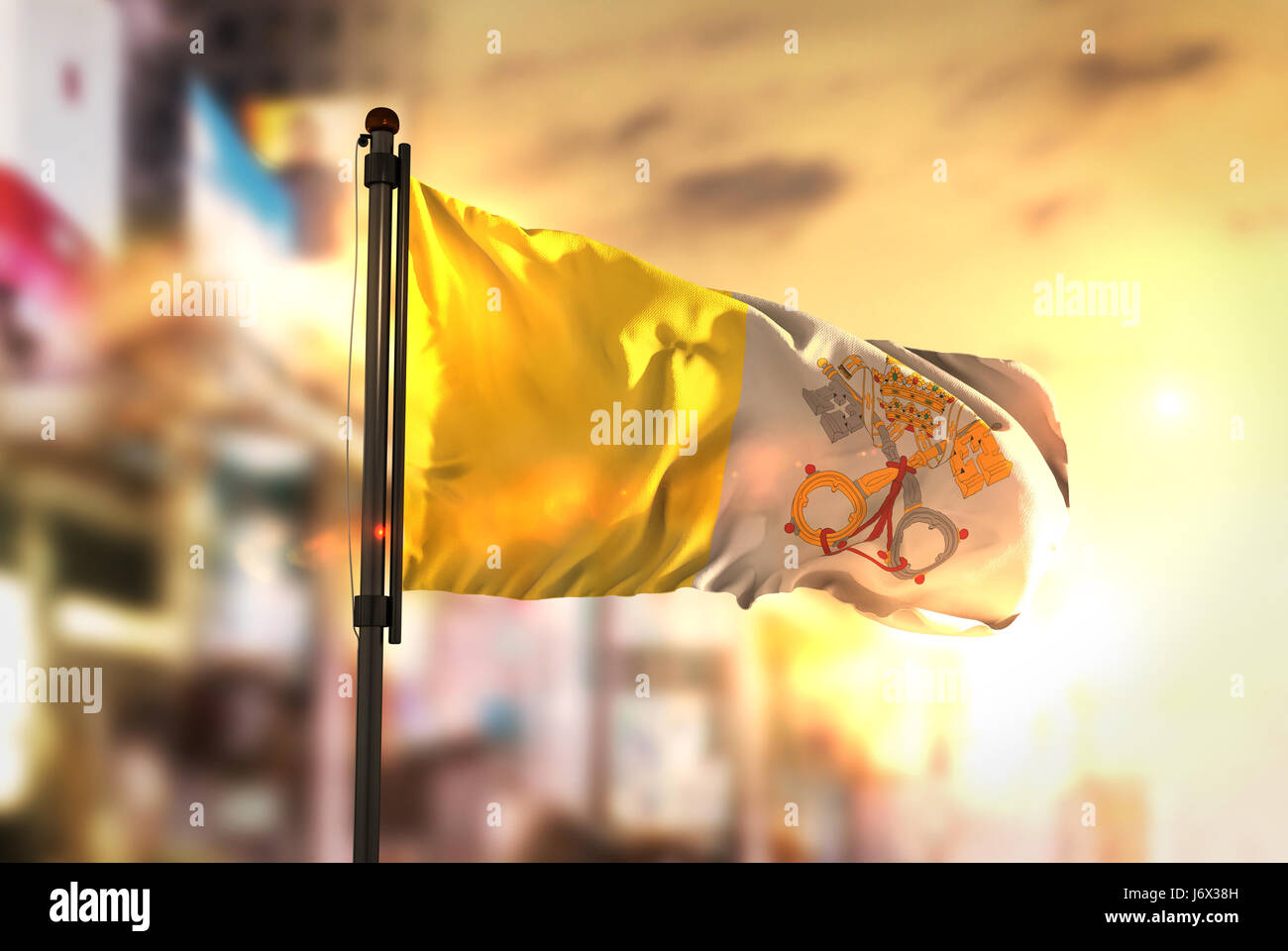Vatikanstadt-Flagge gegen City unscharf Hintergrund bei Sonnenaufgang Hintergrundbeleuchtung Stockfoto