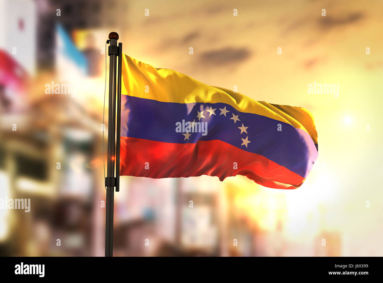 Venezuela-Flagge gegen City unscharf Hintergrund bei Sonnenaufgang Hintergrundbeleuchtung Stockfoto