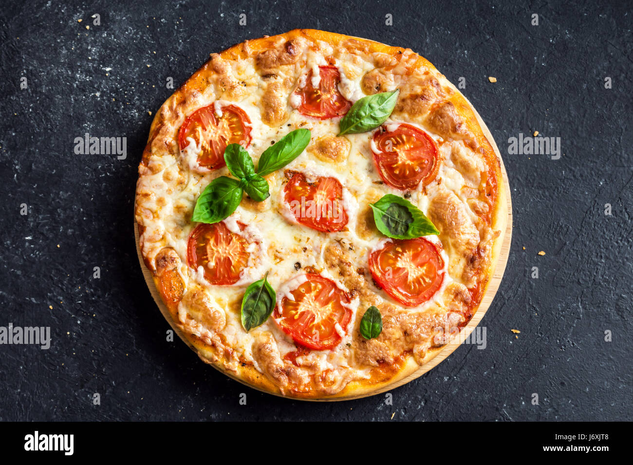 Pizza Margherita auf schwarzem Stein, Ansicht von oben. Pizza Margarita mit Tomaten, Basilikum und Mozzarella-Käse hautnah. Stockfoto