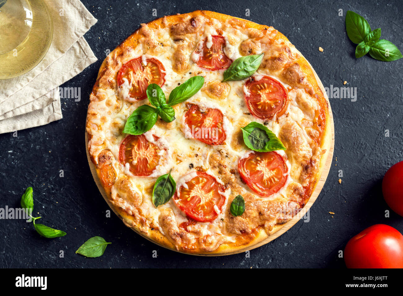 Pizza Margherita auf schwarzem Stein, Ansicht von oben. Pizza Margarita mit Tomaten, Basilikum und Mozzarella-Käse hautnah. Stockfoto