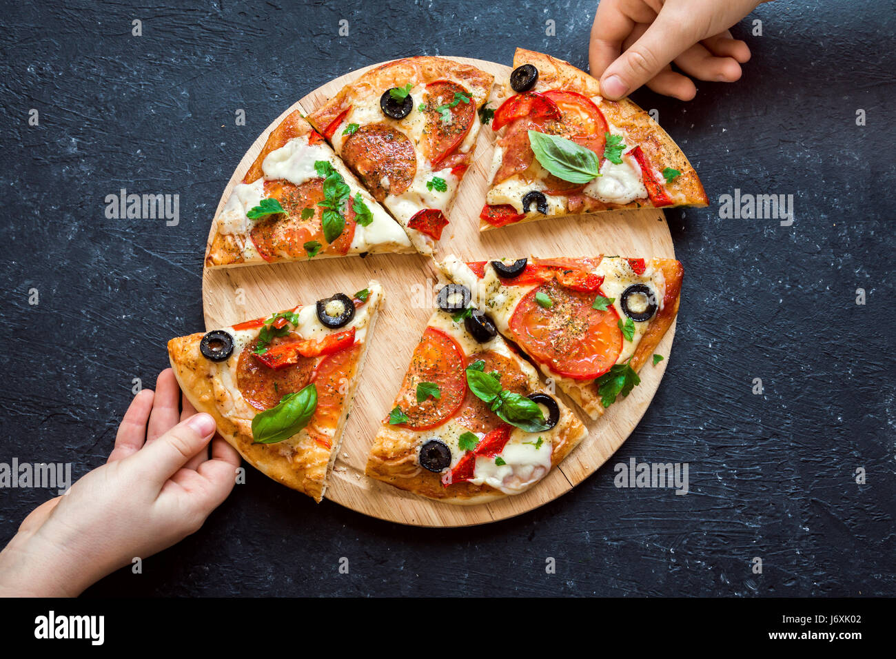Menschen Hände nehmen Scheiben der italienischen Pizza. Italienische Pizza und Hände hautnah auf schwarzem Hintergrund. Stockfoto