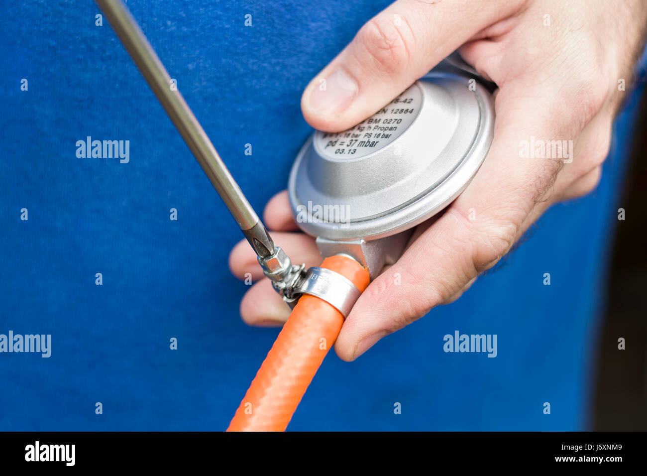 Verschrauben Sie das Spannband mit dem Gummischlauch aus dem Gas-Zylinder-Reduzierstück Stockfoto