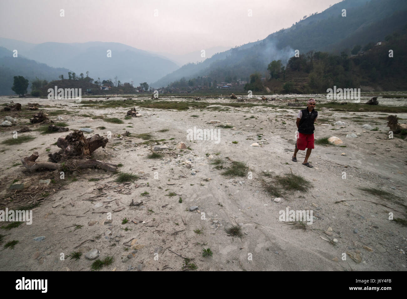 Ein Mann, der durch eine weite Harpan Khola Aue im Kaski Distrikt, Gandaki, Nepal, geht. Stockfoto
