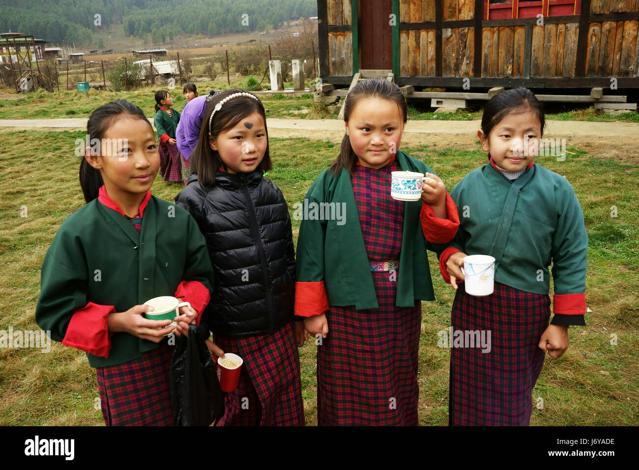 Schulmädchen Teetrinken beim Mittagessen an der Erlemtary School of Phobjika, Bhutan Stockfoto