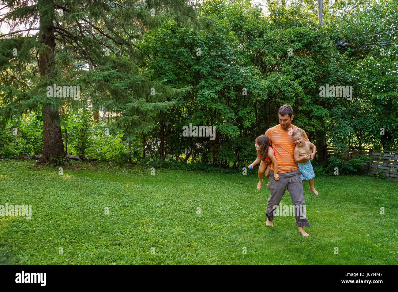 Vater mit zwei Kindern im Garten spielen Stockfoto