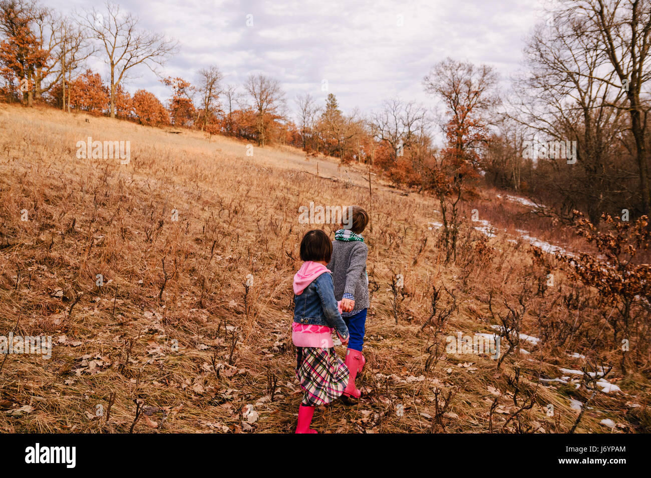 Zwei Kinder auf einem Hügel, Hand in Hand laufen Stockfoto