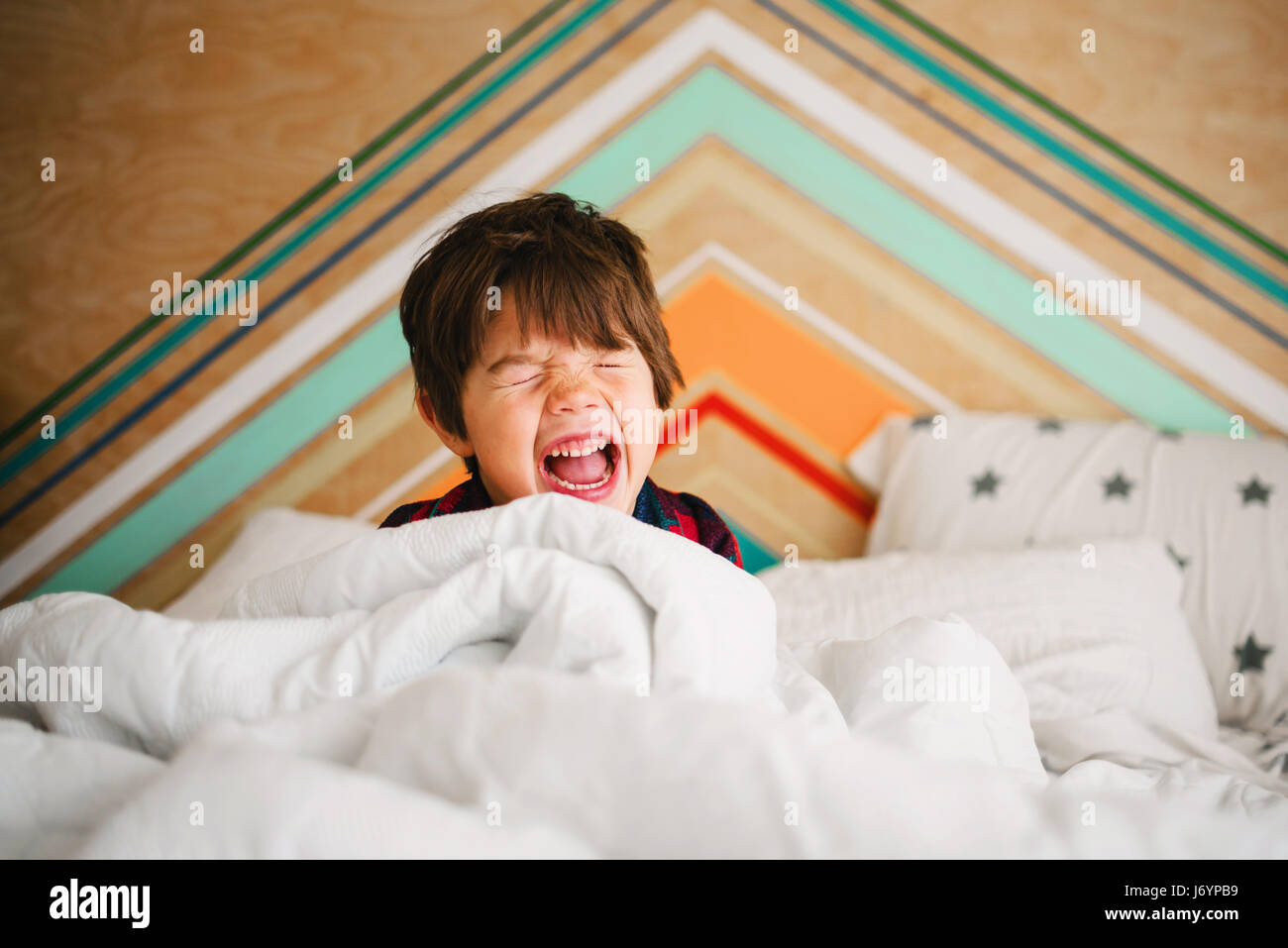 Junge im Bett sitzend, der einen Wutanfall hat Stockfoto