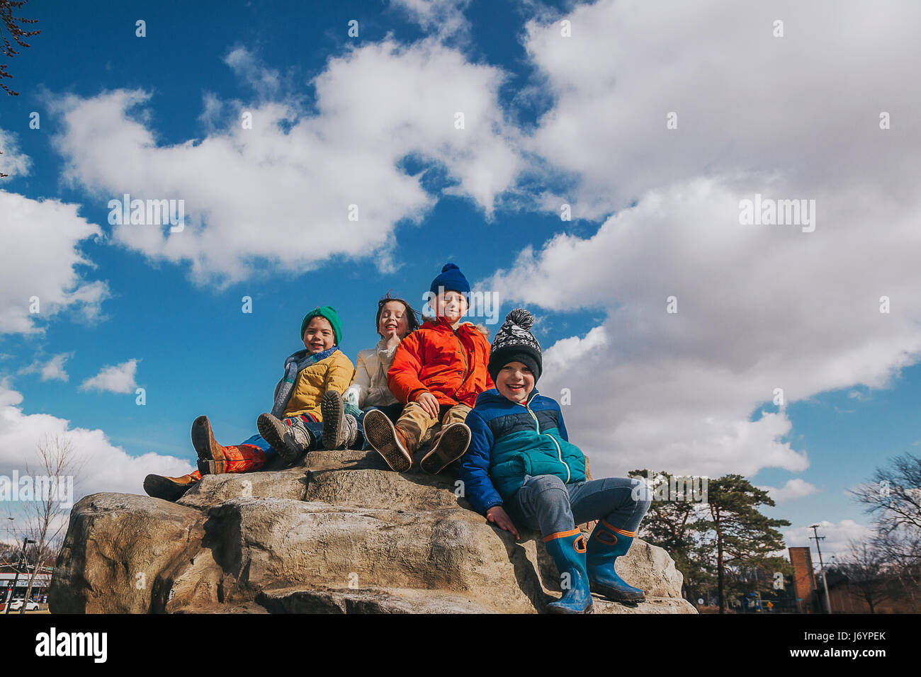 Vier Kinder sitzen auf der Oberseite ein Kletterfelsen auf einem Spielplatz Stockfoto