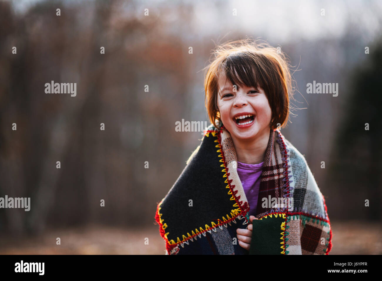 Porträt eines Mädchens, eingewickelt in eine Decke lachen Stockfoto