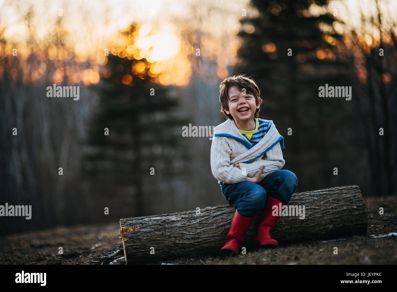 Junge sitzt auf einem Protokoll vor Lachen Stockfoto