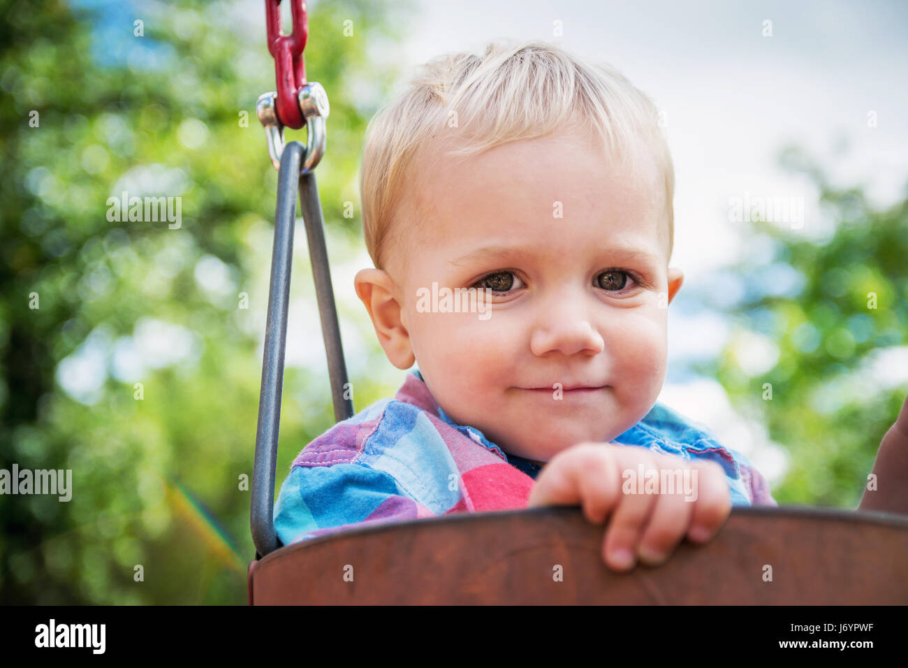 Portrait eines lächelnden jungen sitzen in einem Schwung Stockfoto