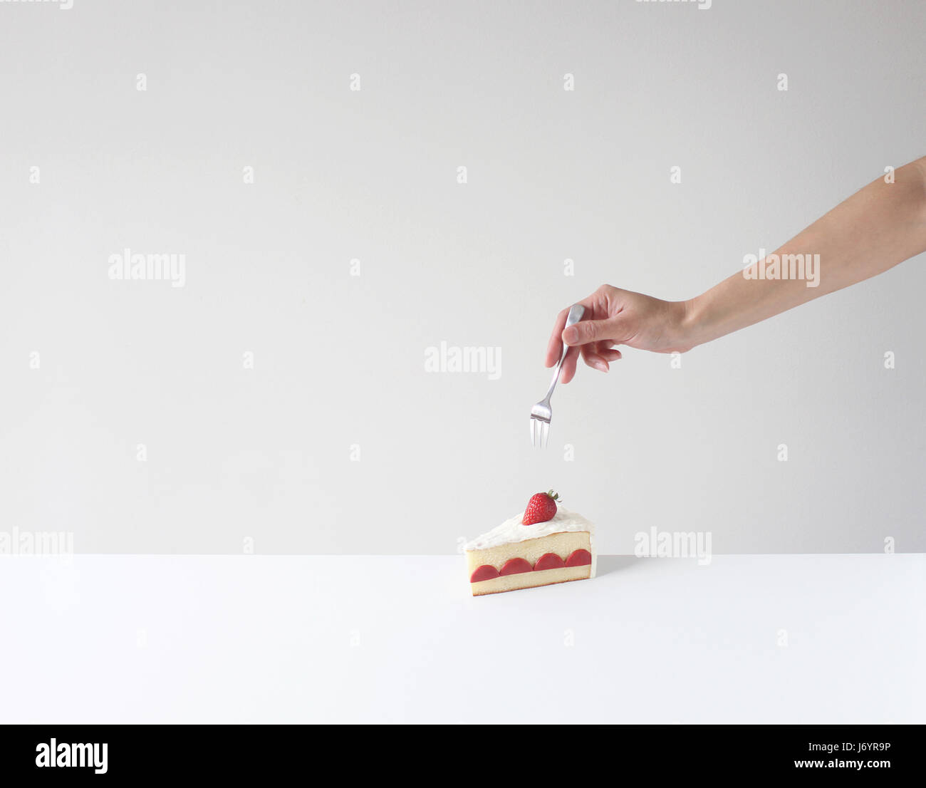 Hand mit einer Gabel zu einem Stück Kuchen zu essen Stockfoto