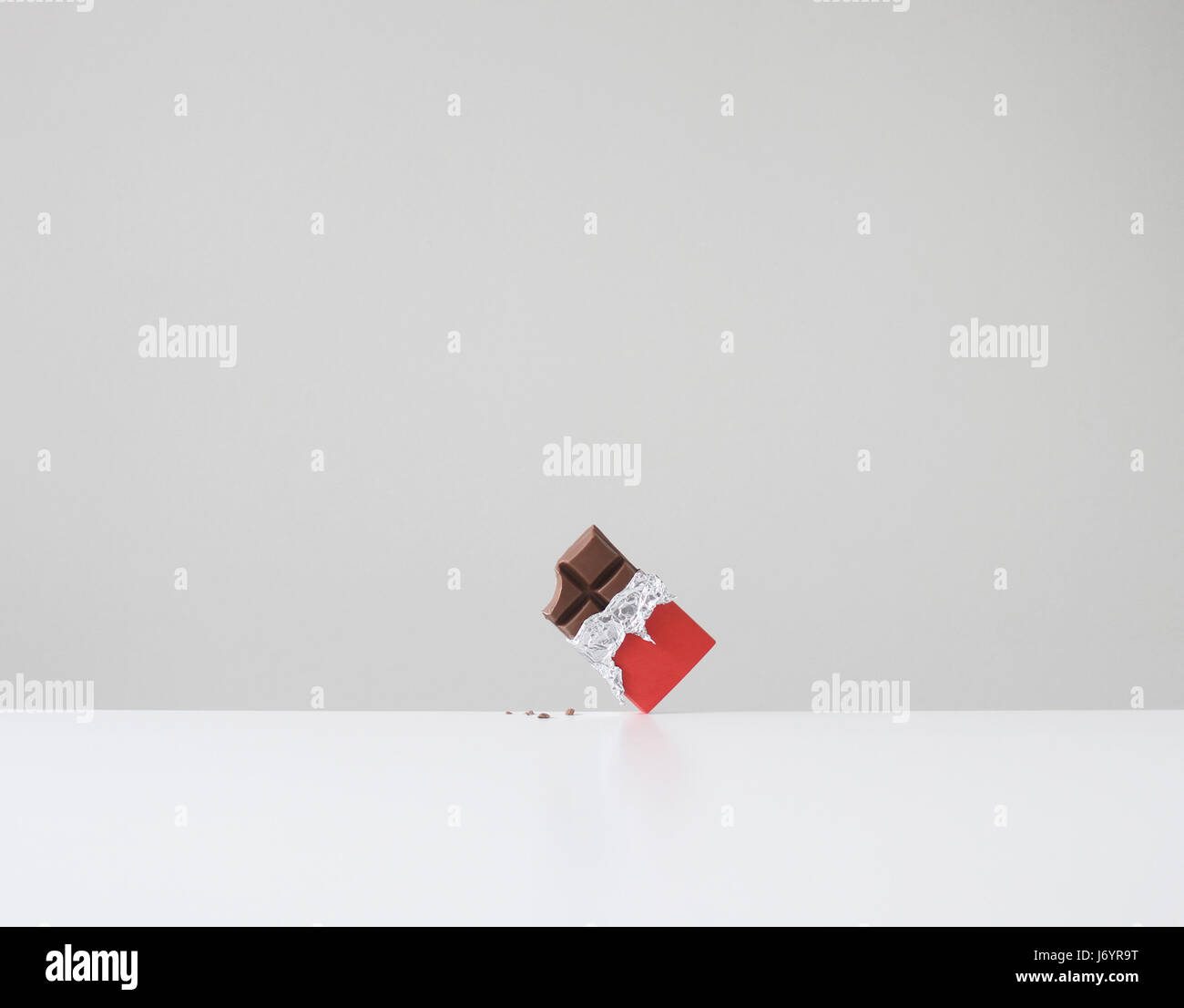 Schokoriegel mit fehlenden Biss und Schokolade Krümel auf Tisch Stockfoto
