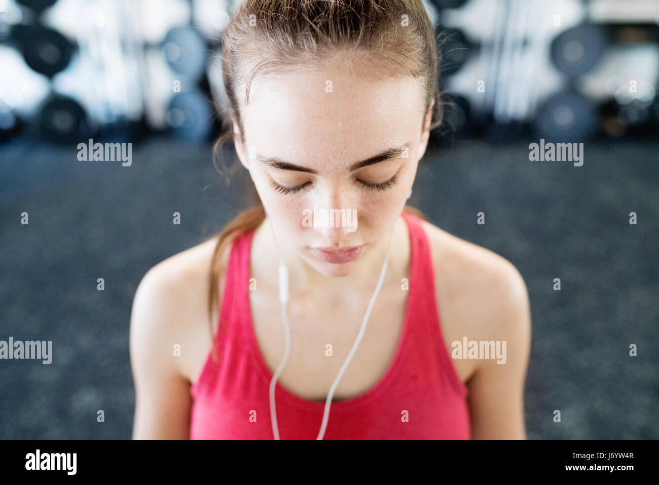 Junge Frau im Fitness-Studio, Kopfhörer in den Ohren, Musik hören Stockfoto