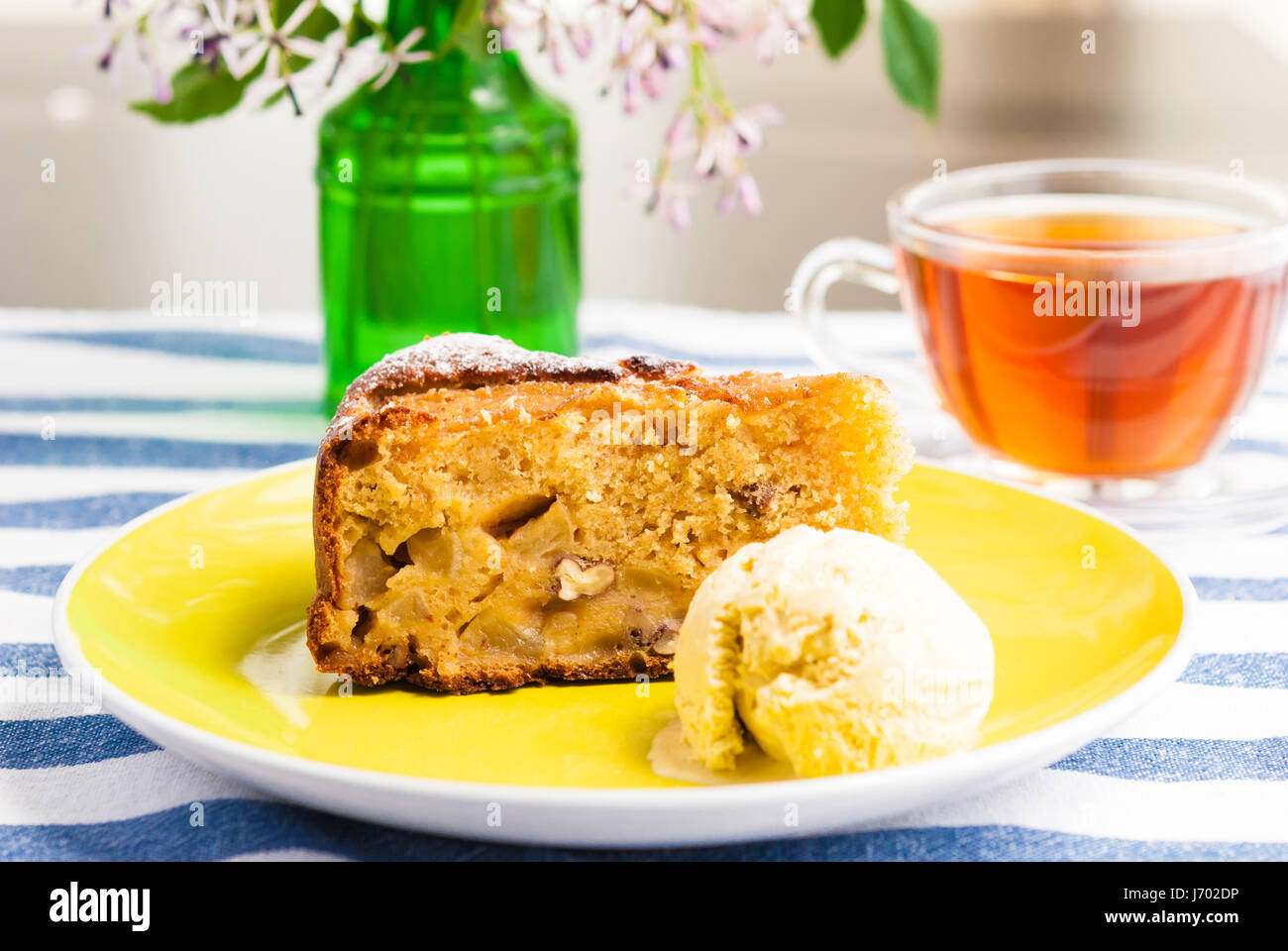 Stück vom süßen hausgemachten Apfelkuchen mit Eis und eine Tasse Tee serviert Stockfoto