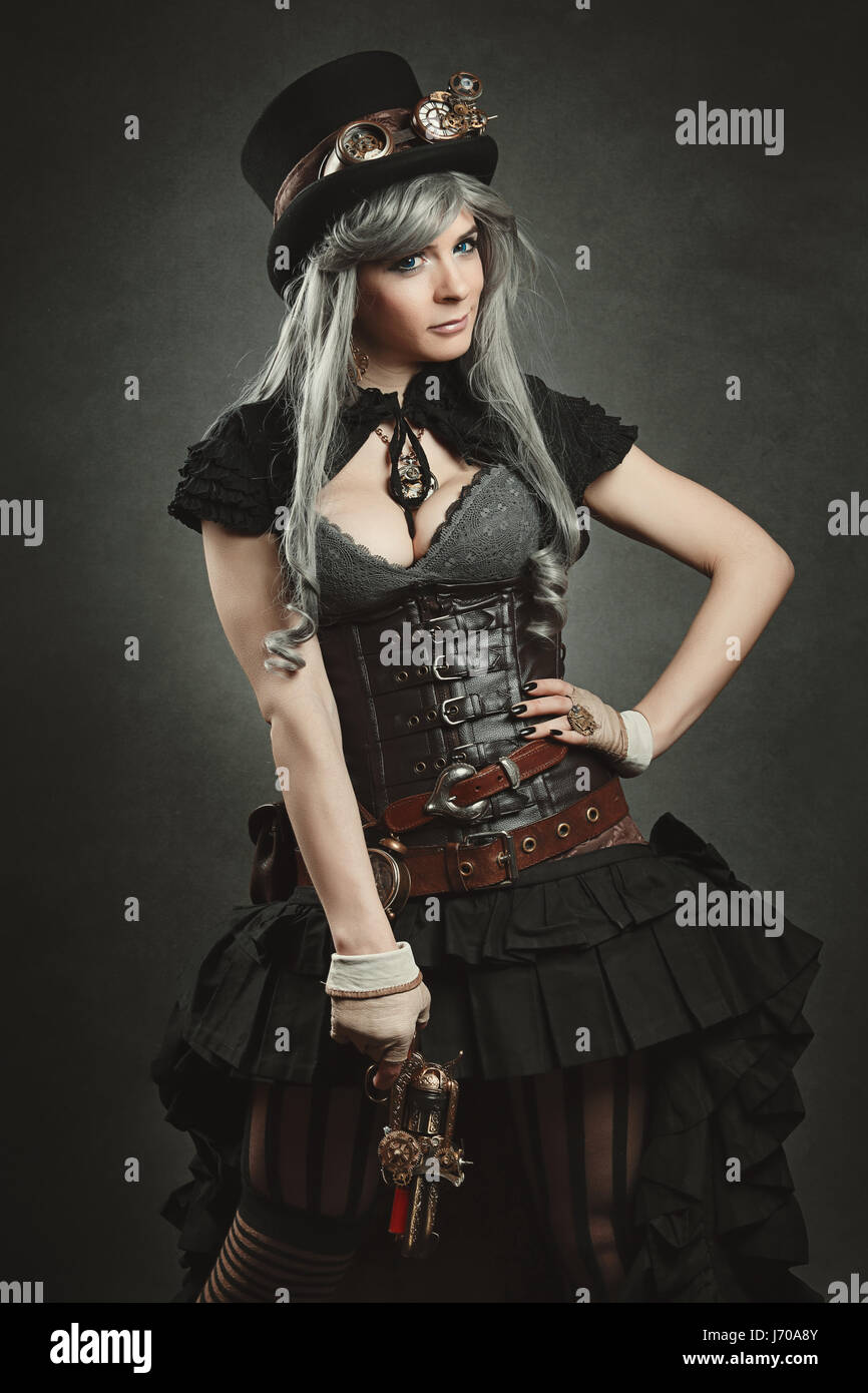 Schöne Frau posiert mit Steampunk Gewehr und Kleid. Texturierte Hintergrund Stockfoto