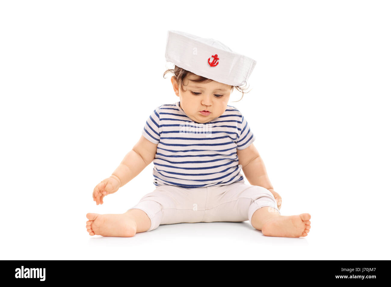 Babymädchen, gekleidet in einem Matrosen Outfit sitzen auf dem Boden isoliert auf weißem Hintergrund Stockfoto