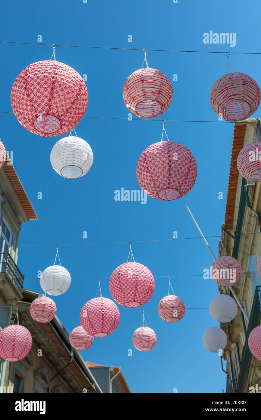 Rosa kugelförmige Lampions aufgehängt in Porto Straße zwischen den Häusern, Portugal Stockfoto