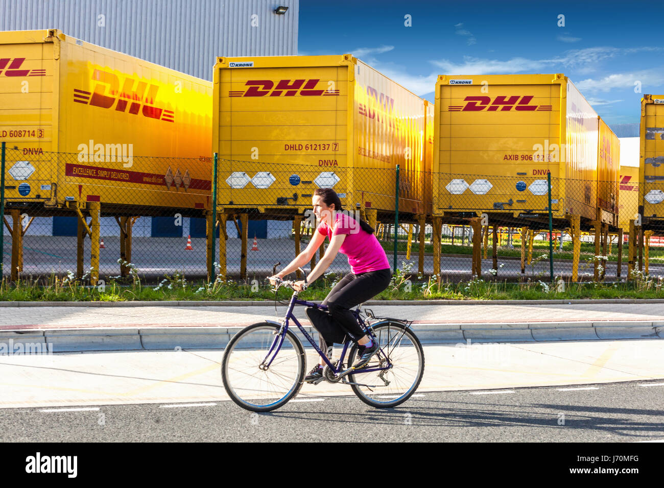 Frau biker vorbei um DHL Shipping Container. Dobroviz, Tschechische Republik, Europa Stockfoto