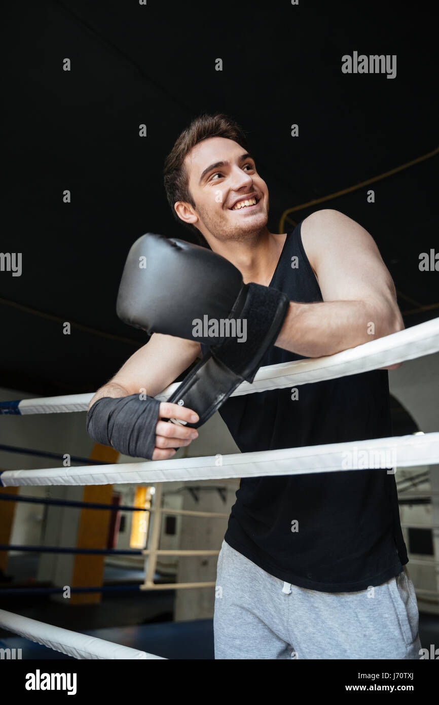 Lächelnde junge Boxer tragen Boxhandschuhe und wegsehen Stockfoto