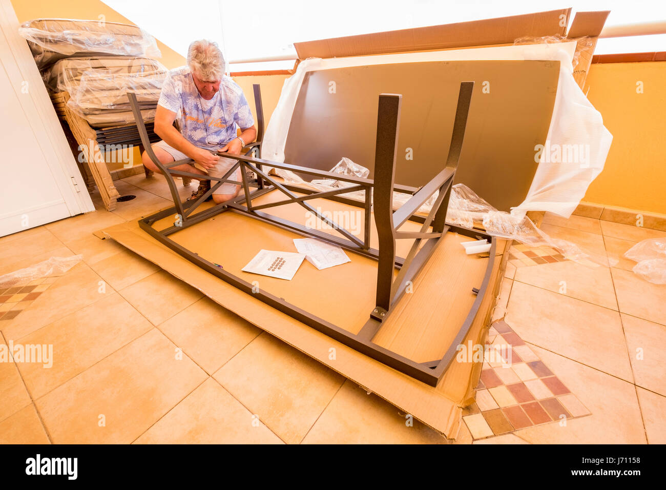 Mann mittleren Alters, Montage flach verpackt Tisch auf der Terrasse Stockfoto