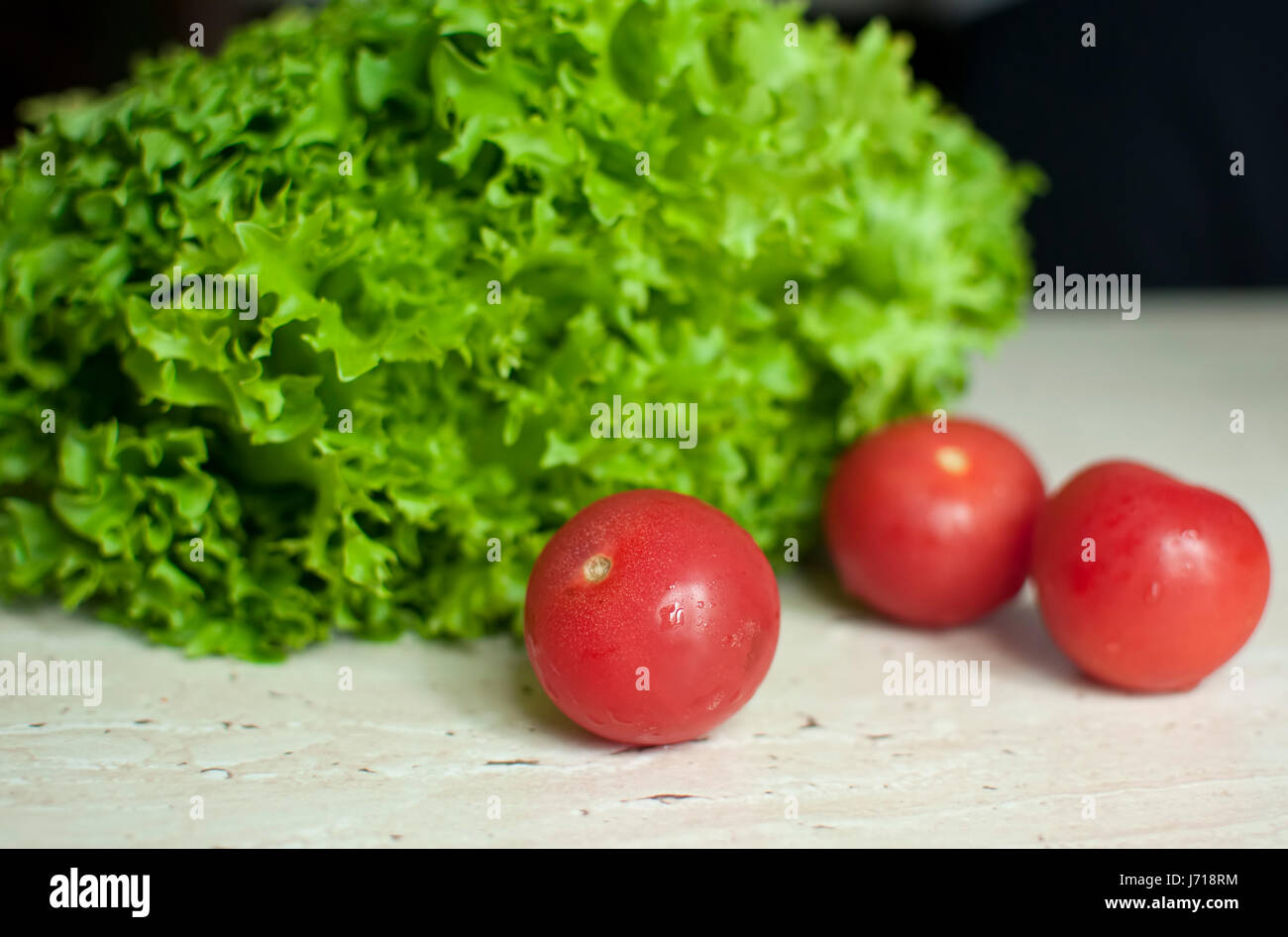 Reihe von rohen Bio grüne Frisee Salat und drei Tomaten auf Holztisch. Selektiven Fokus. Stockfoto