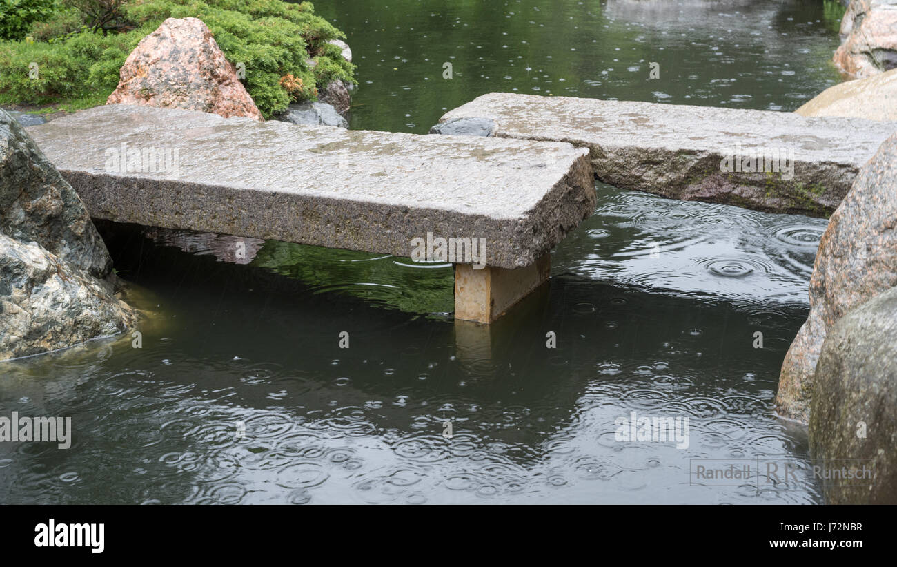 Eine Steinbrucke Uberquert Einen Teich In Eine Japanische Garten