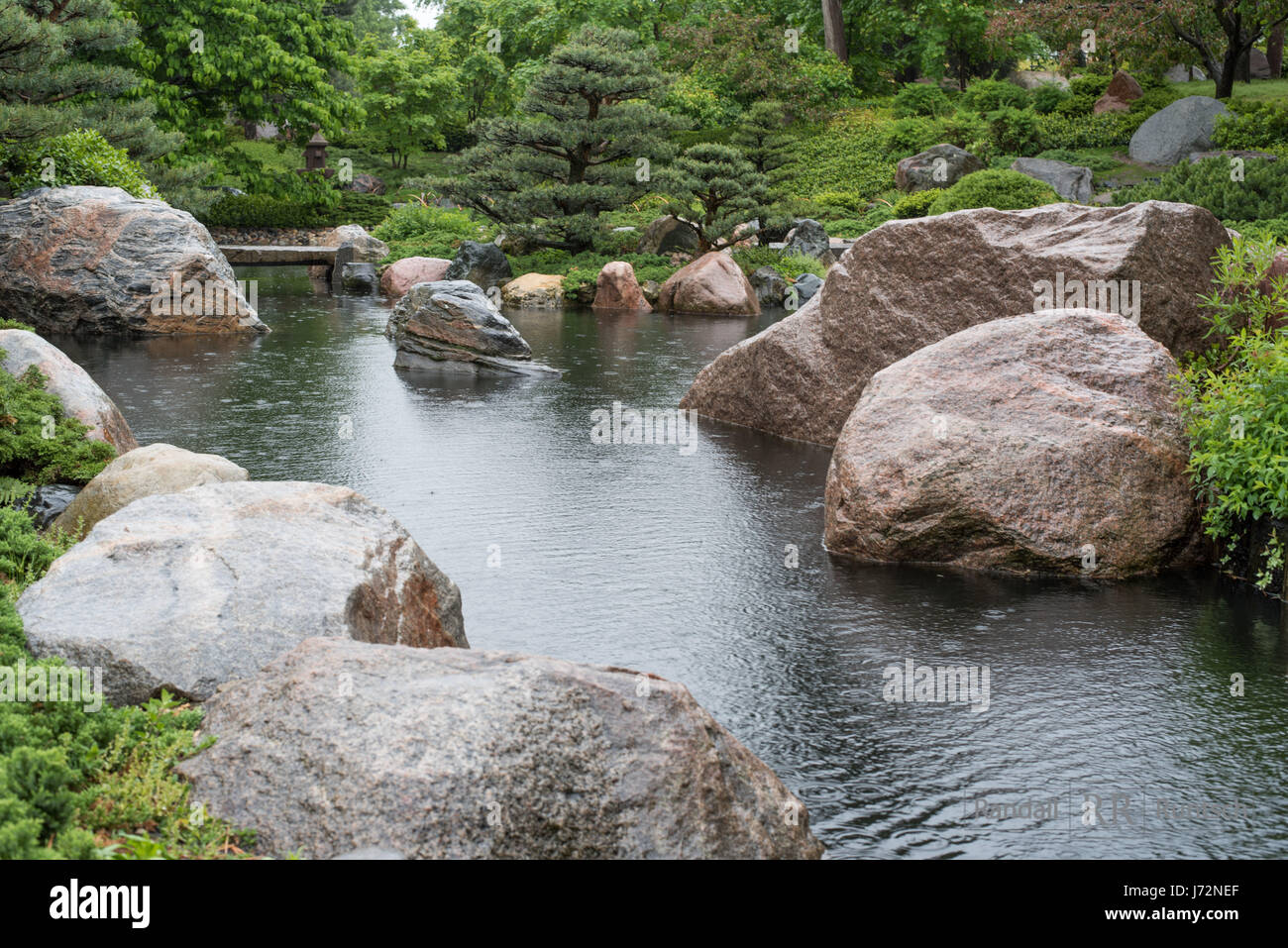 Eine Steinbrucke Uberquert Einen Teich In Eine Japanische Garten