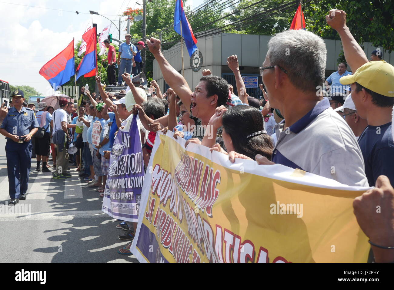 Demonstranten halten ihre Schilder vor LTFRB Büro, während ein Polizist den Verkehr manning ist. (Foto: George Buid/Pacific Press) Stockfoto