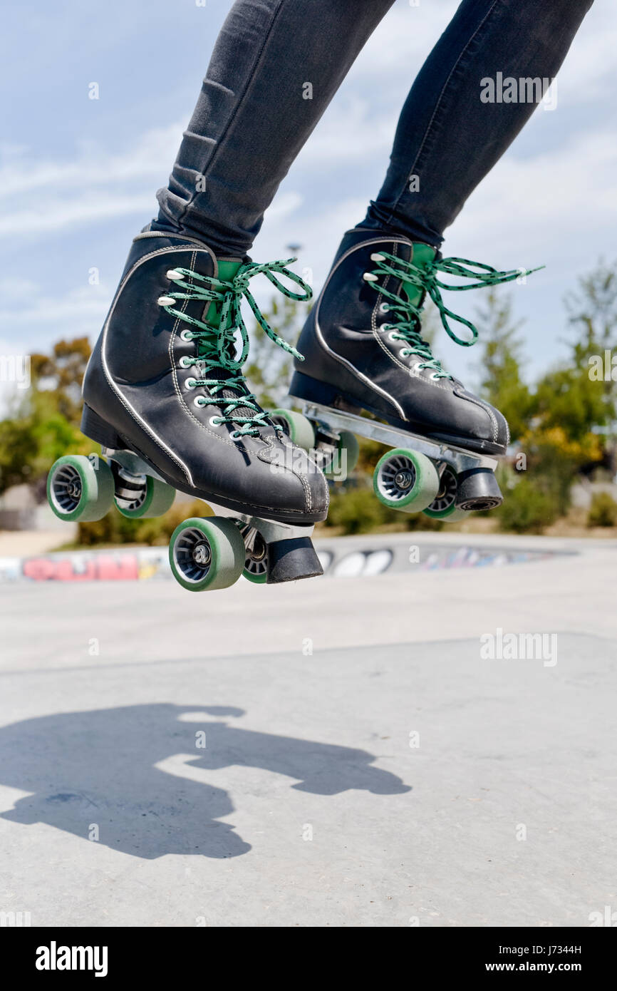 Closeup von einem kaukasischen Jüngling Rollschuhlaufen mit Quad Skates springen in ein Outdoor-Skate-park Stockfoto