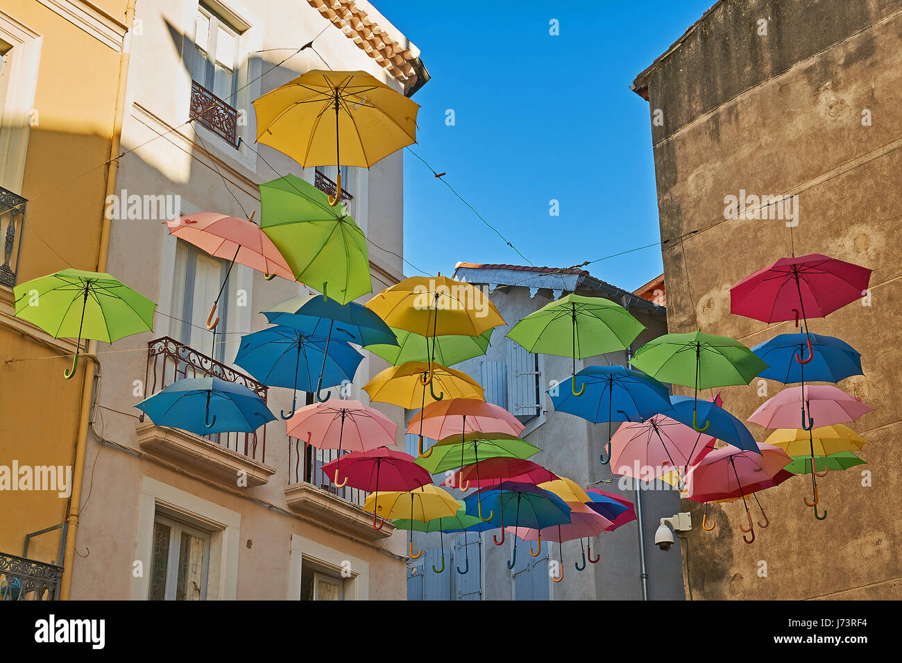Bunte Schirme hängen zwischen den Gebäuden oberhalb einer Straße in der Altstadt von Beziers, Frankreich Stockfoto