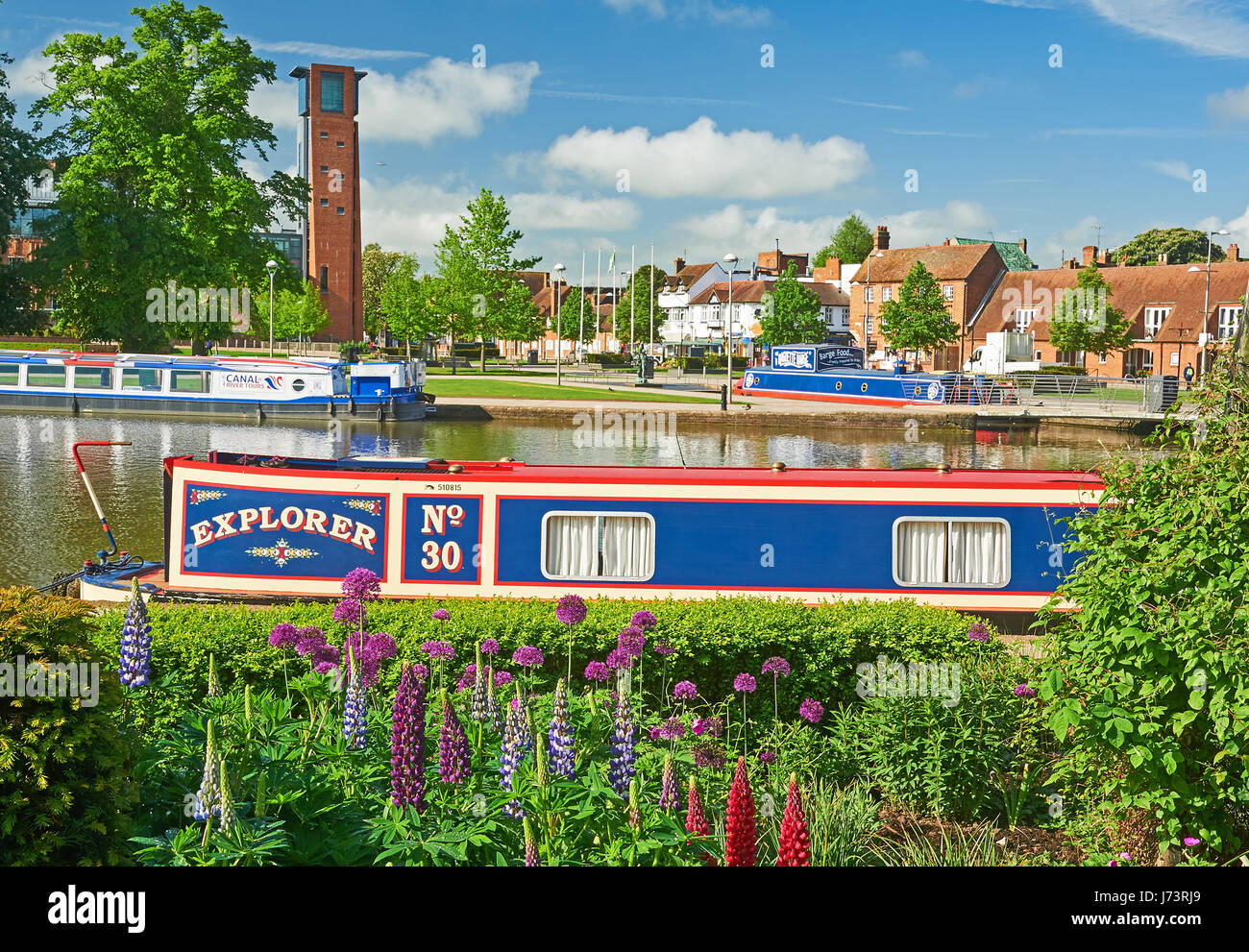 Hausboote in Bancroft-Becken in Stratford-upon-Avon mit dem Turm für das Royal Shakespeare Theatre im Hintergrund Stockfoto