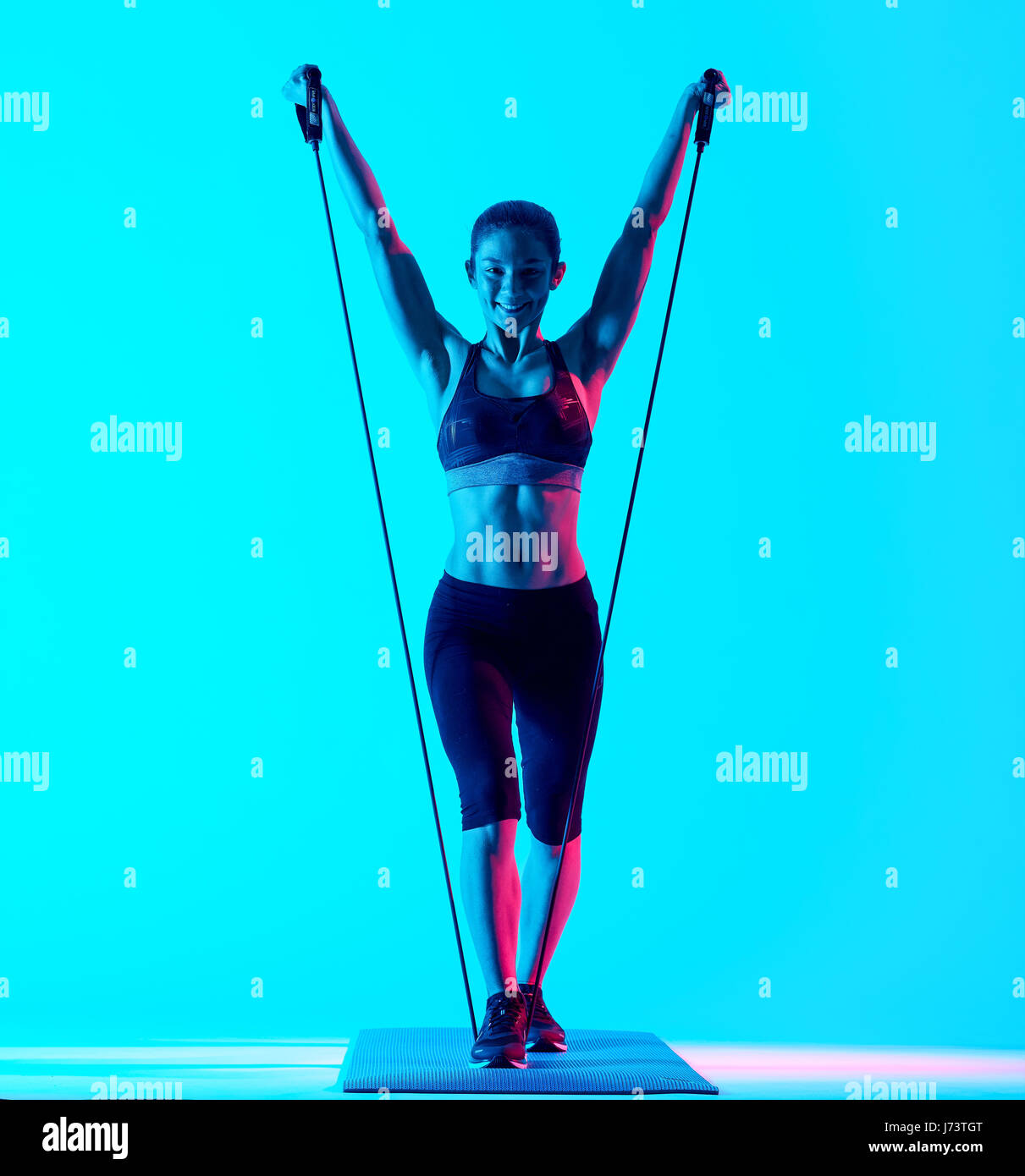 eine gemischtrassige Frau Exercsing Fitness Gummibänder Übungen auf blauen Blackground isoliert Stockfoto