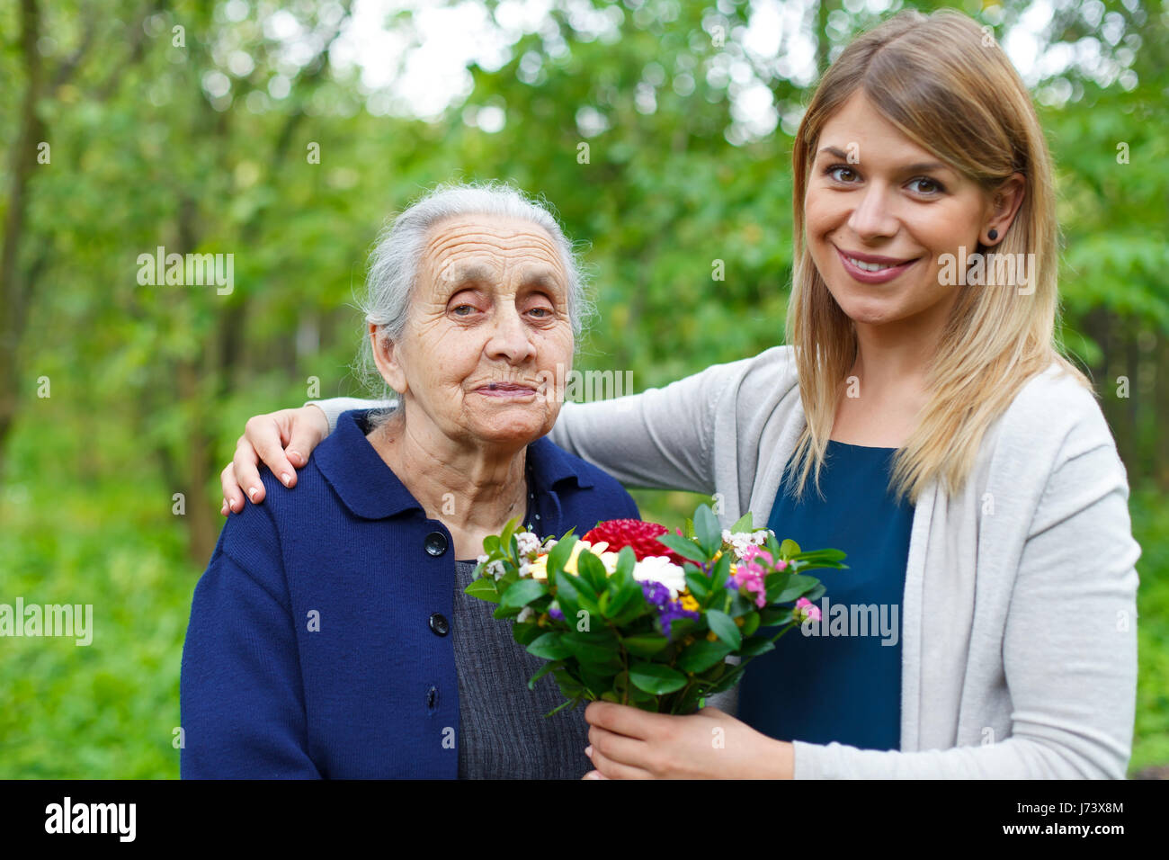 Porträt einer gerne ältere Frau, die Blumen von ihrer Enkelin Stockfoto