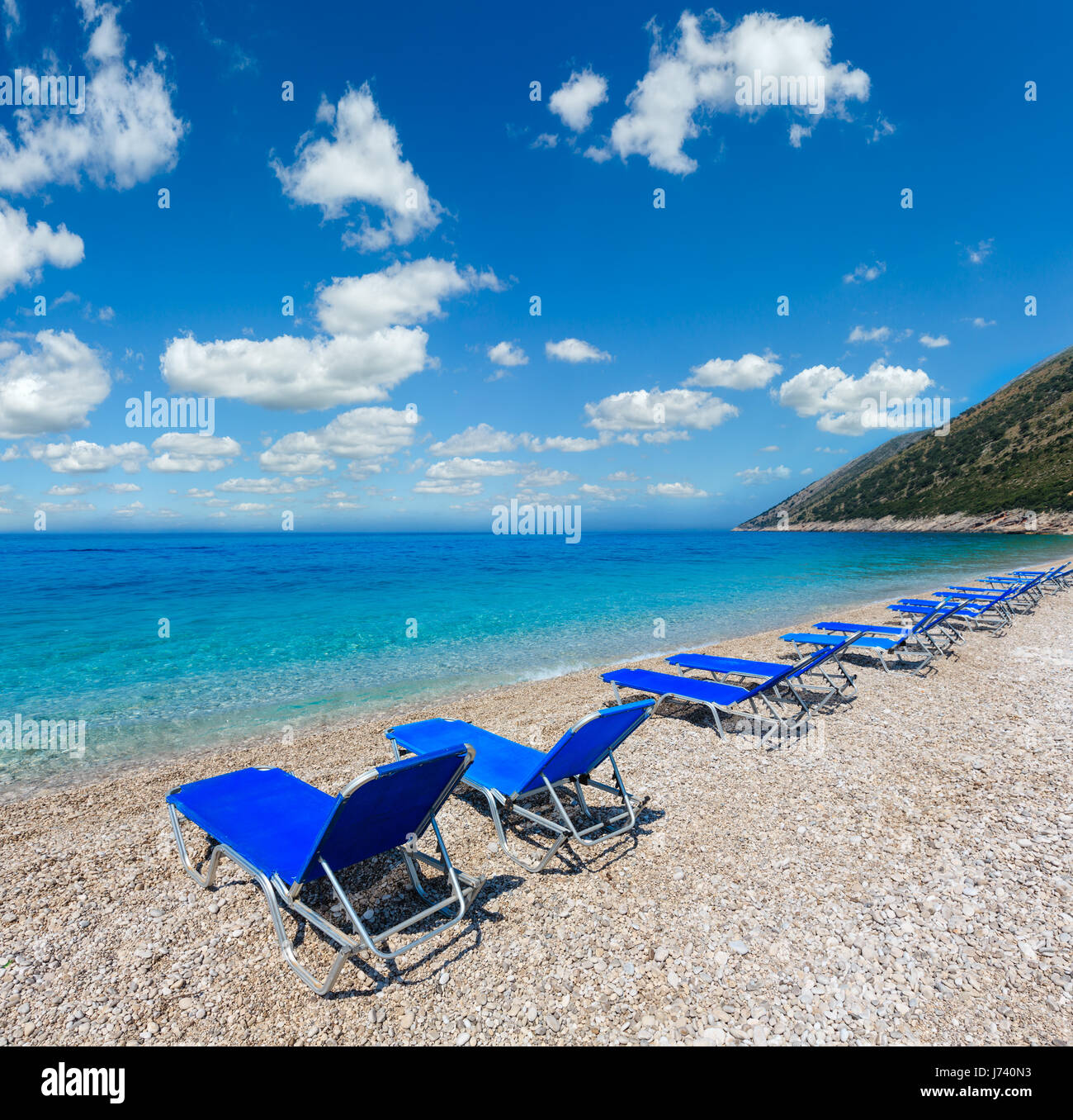 Sommer morgen kiesiger Strand mit Sonnenliegen (Albanien). Stockfoto