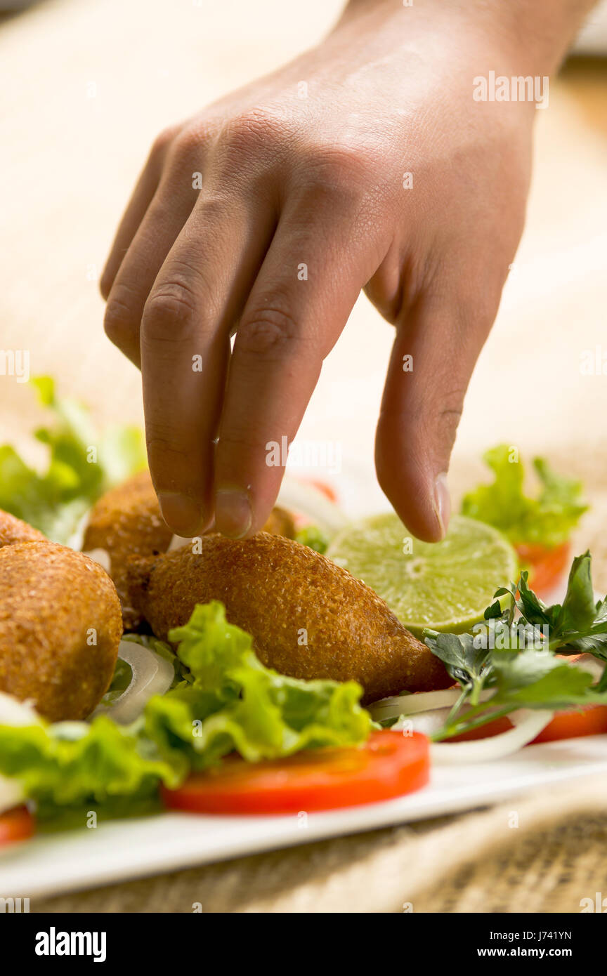 Mann seine Hand benutzen, um eine köstliche türkische Ramadan nehmen Nahrung Icli Köfte Frikadelle Falafel. Stockfoto