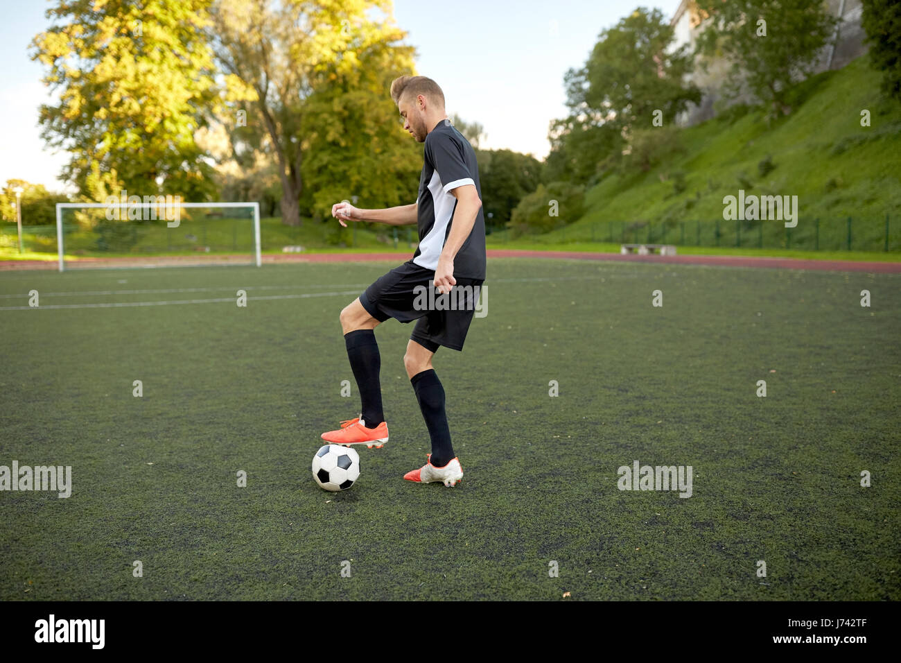 Fußballspieler mit Ball auf Fußballplatz spielen Stockfoto