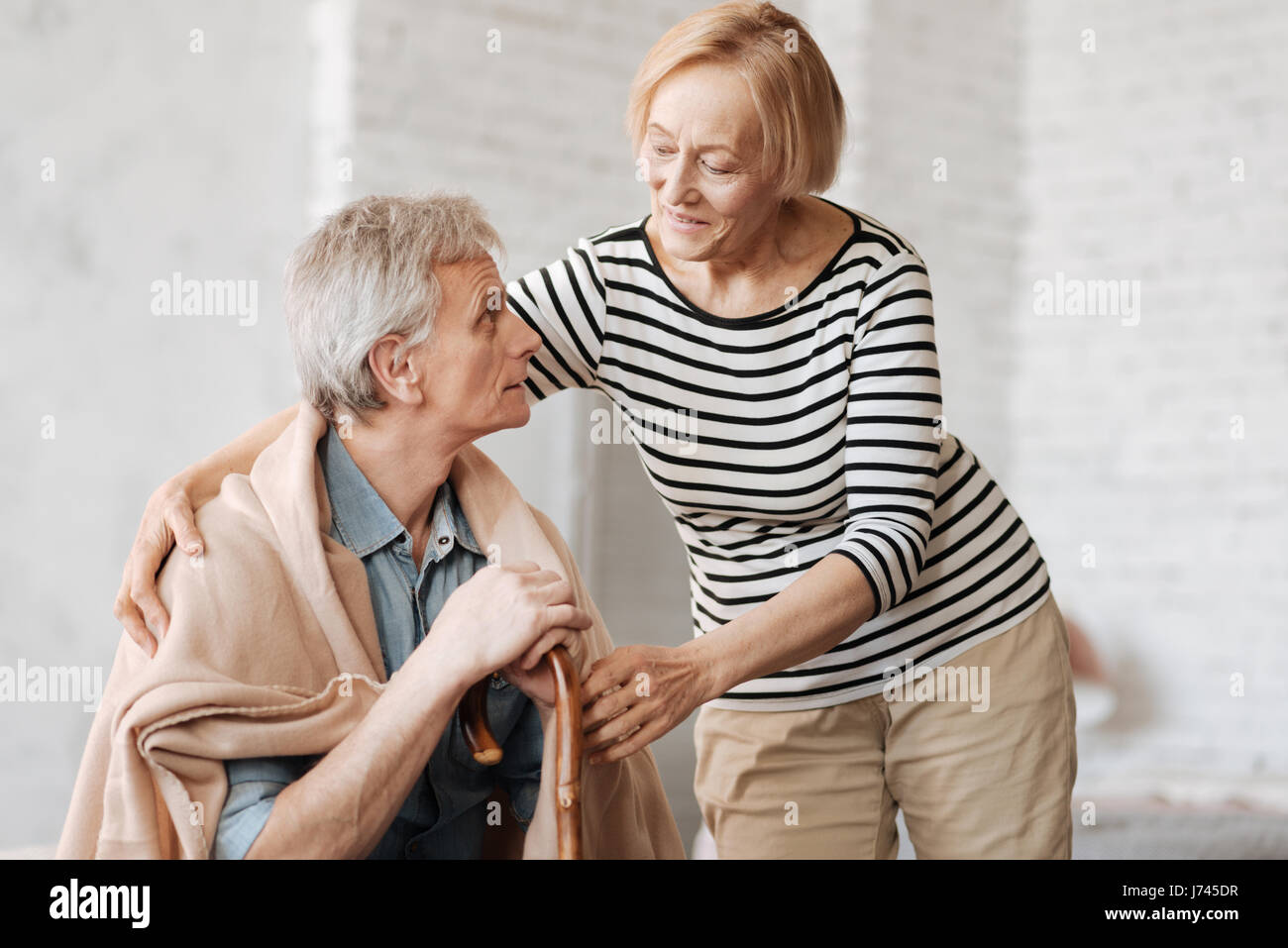 Anmutige liebevolle Dame kümmert sich um ihren Mann Stockfoto