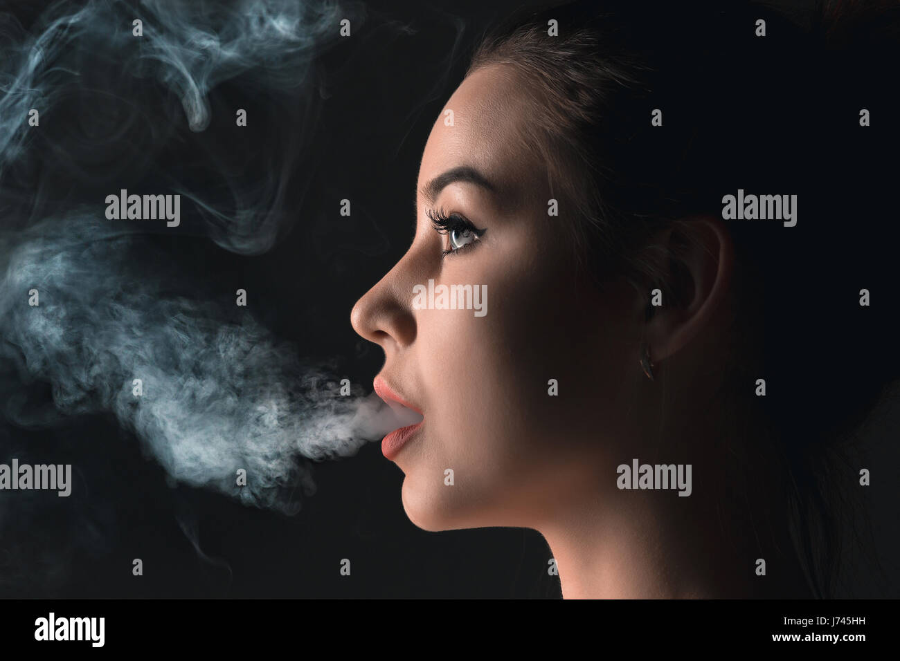 Das Gesicht des dampfen junge Frau im schwarzen studio Stockfoto