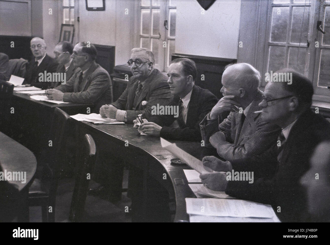 Das Bild aus den 1950er Jahren zeigt männliche Stadträte, die Jacke und Krawatten tragen, an einem geschwungenen Holztisch sitzen, mit dem Protokoll oder der Tagesordnung, in der Kammer bei einer Sitzung des bezirksrats in Aylesbury, England, Großbritannien. Stockfoto