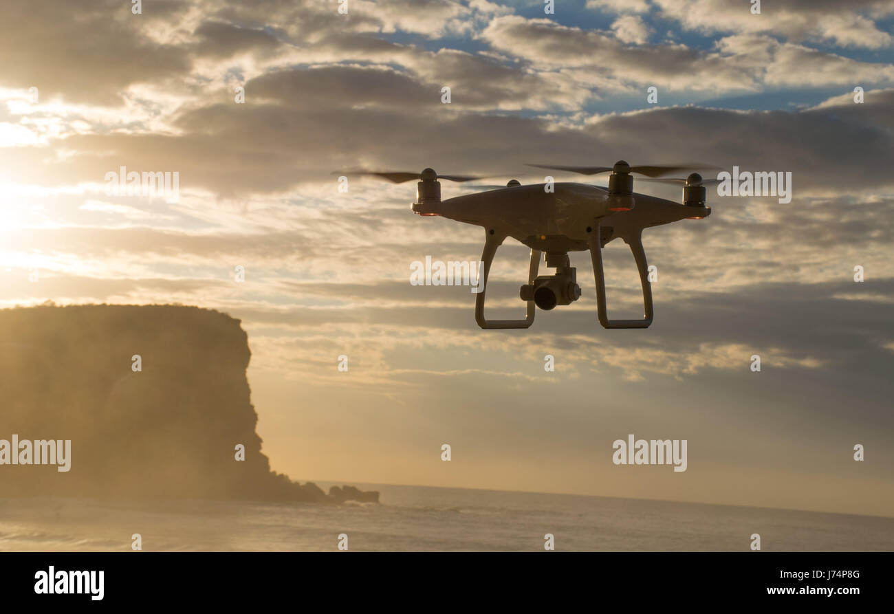 Eine Drohne schwebt über den Ozean, als die Sonne aufgeht Stockfoto