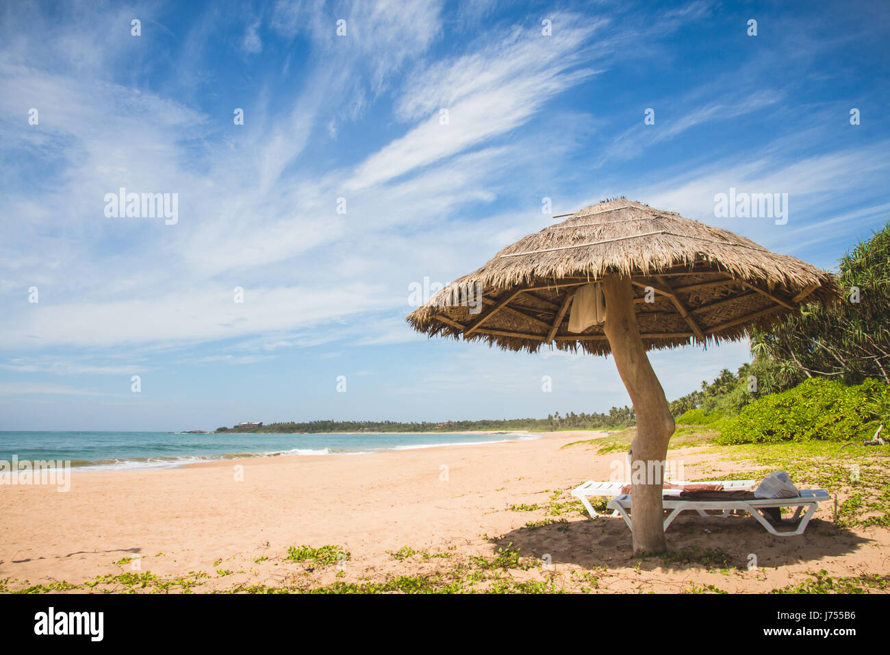Ein Strohschirm und Liegestuhl am Strand von Kahandamodara, außerhalb von Tangalle, Sri Lanka. Stockfoto