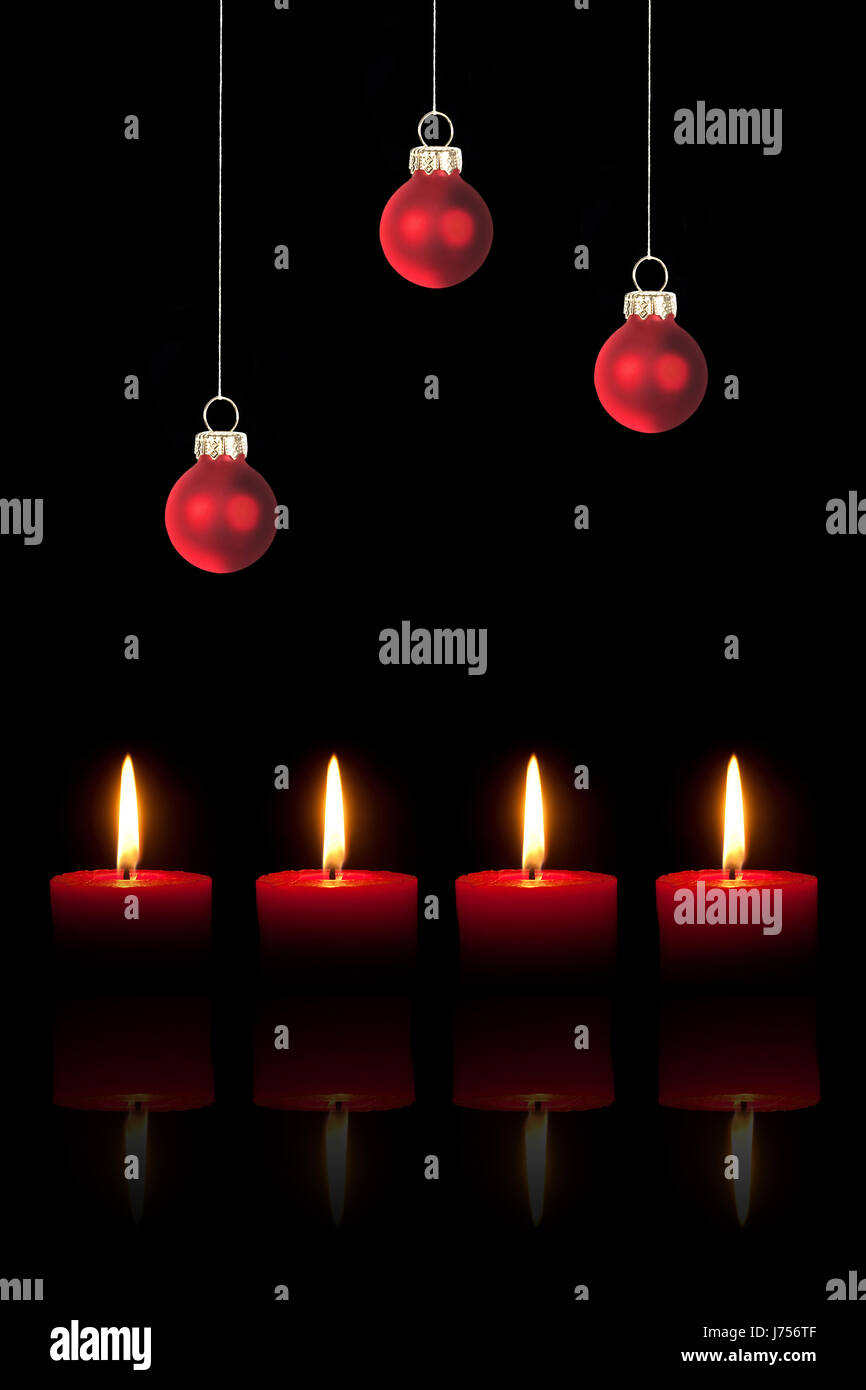 drei rote Christbaumkugeln und vier roten Kerzen Stockfoto