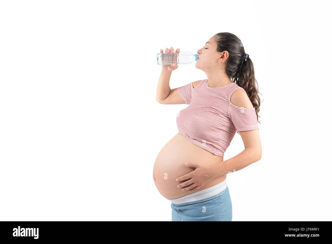 Die junge schwangere Frau mit einem Glas Wasser Stockfoto