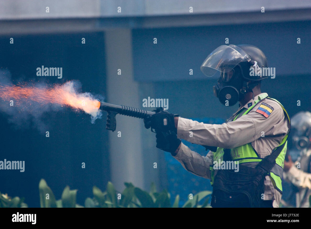 Ein Polizist feuert einen Kanister Tränengas gegen Demonstranten während einer Protestaktion gegen die Regierung von Nicolas Maduro in Caracas. Stockfoto