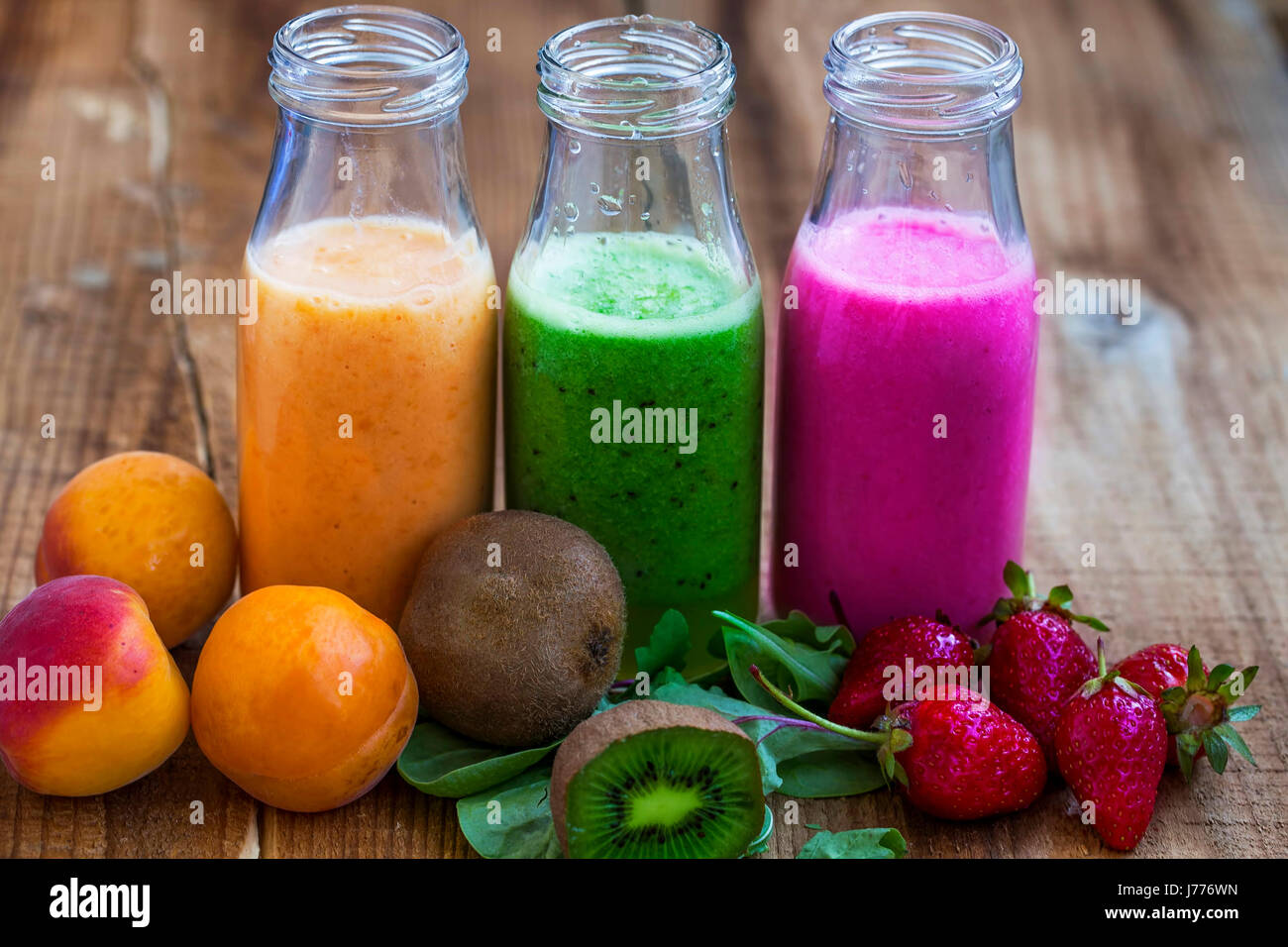 Frische gesunde drei Arten von Früchten Säfte oder Smoothies, Orange, grün und Pink mit Erdbeeren, Aprikosen, Kiwi und Spinat Stockfoto